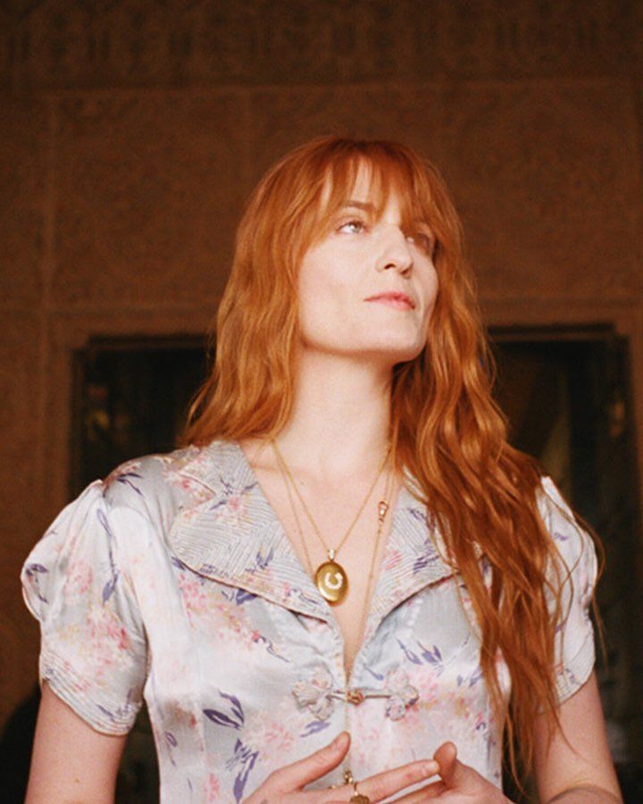 Florence Welch with long bangs in a floral top.