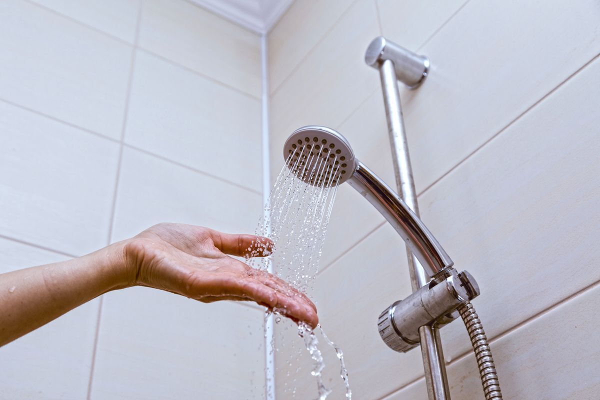 A hand checking the temperature of shower water.