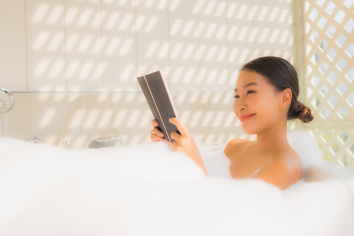 Asian woman reading a book in the bath