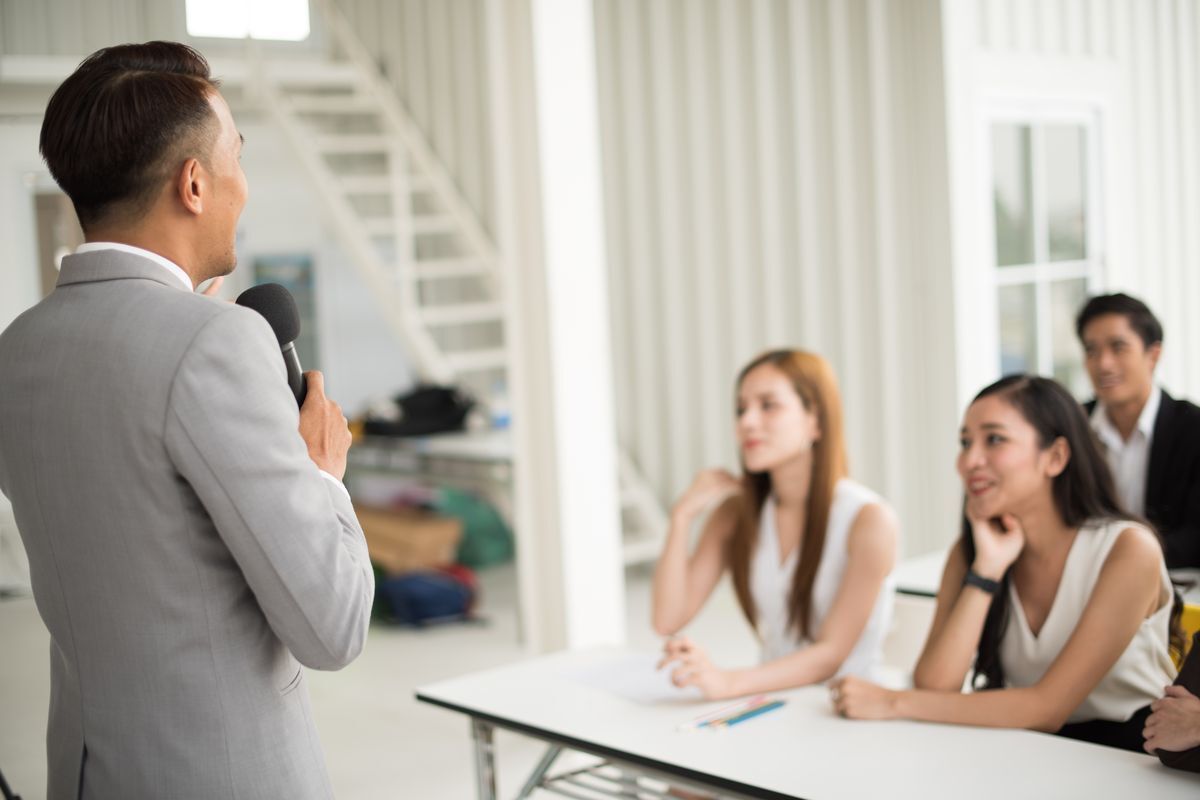 Asian man speaking at a group.