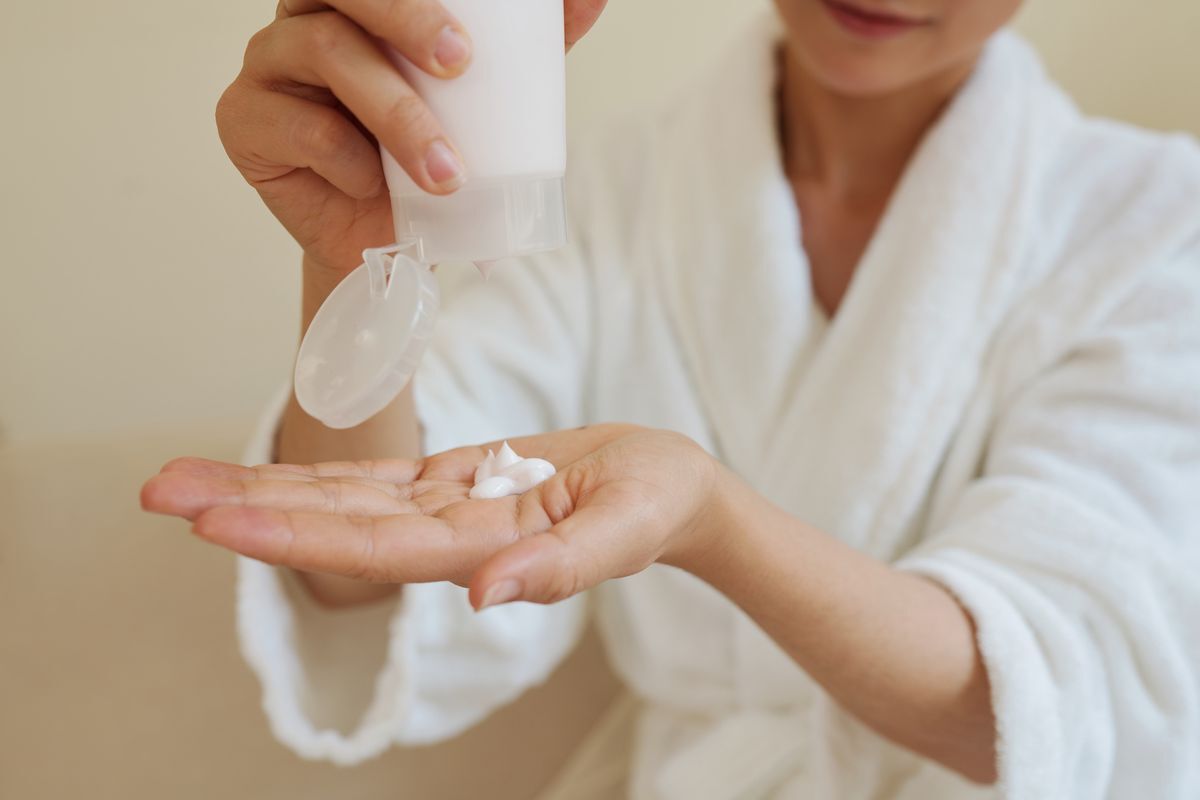 Asian woman squeezing hand cream onto her palm.
