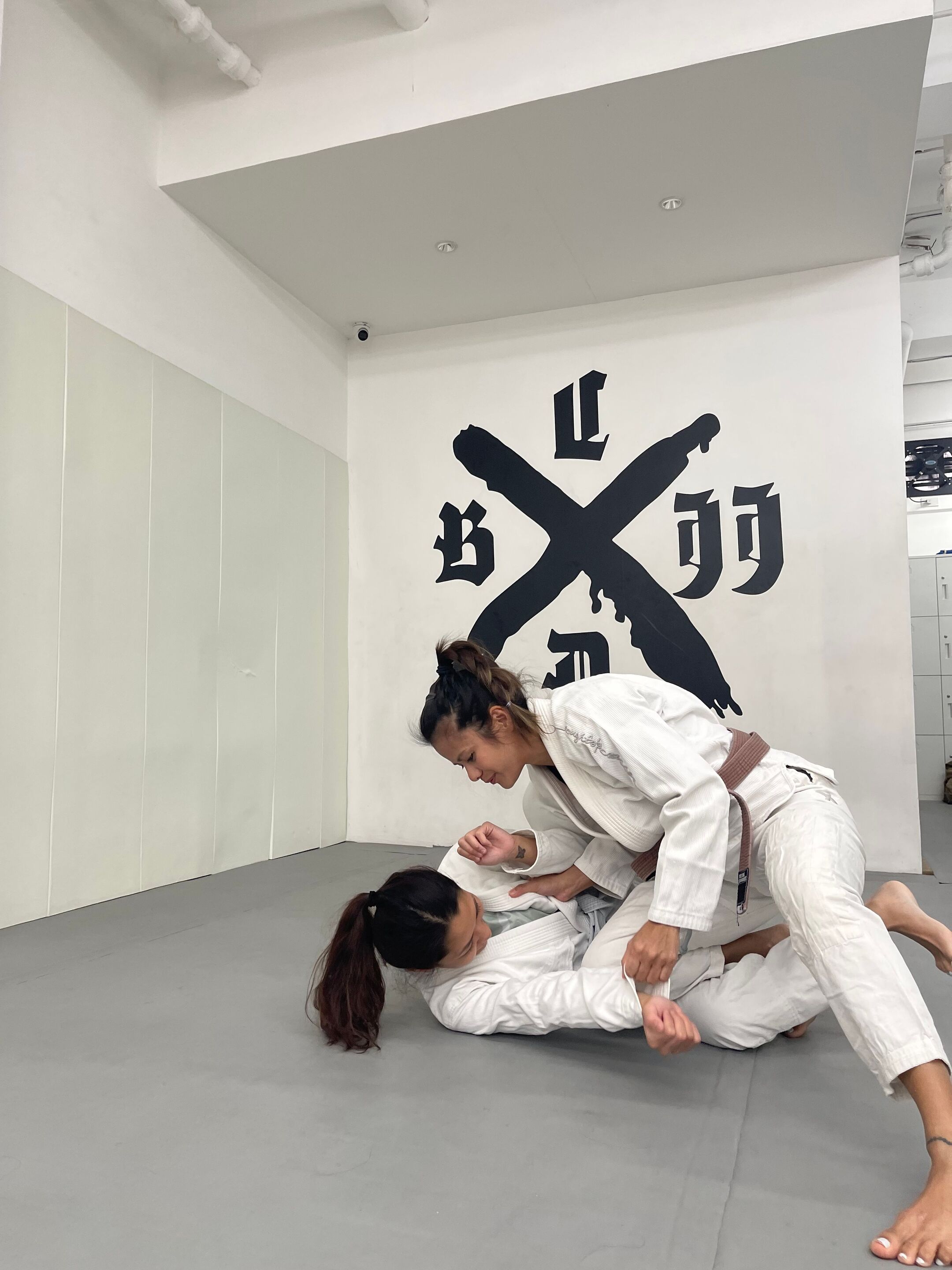 Two Asian women practicing Brazilian jiu-jitsu.