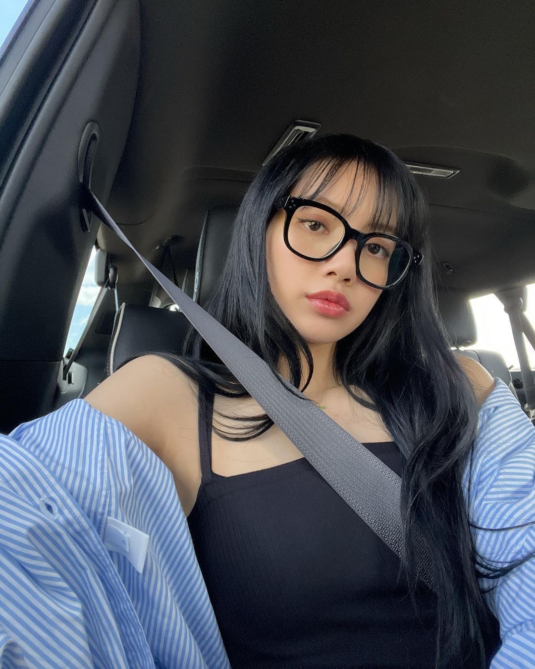 Woman with bangs and long black hair wearing glasses.