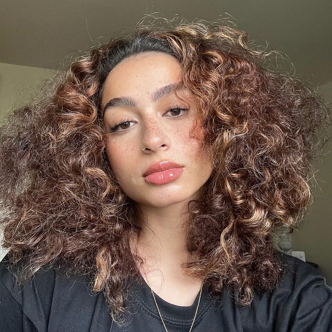 Woman with curly hair and feathery eyebrows.