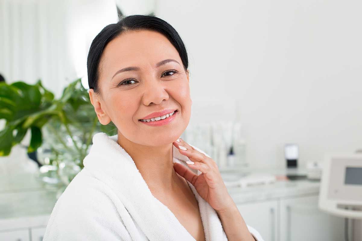 A smiling woman touching her neck