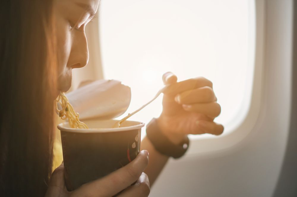 Asian woman eating instant noodles on a plane