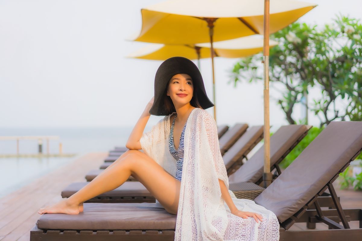 A woman in a swimsuit and coverup hanging out at the beach