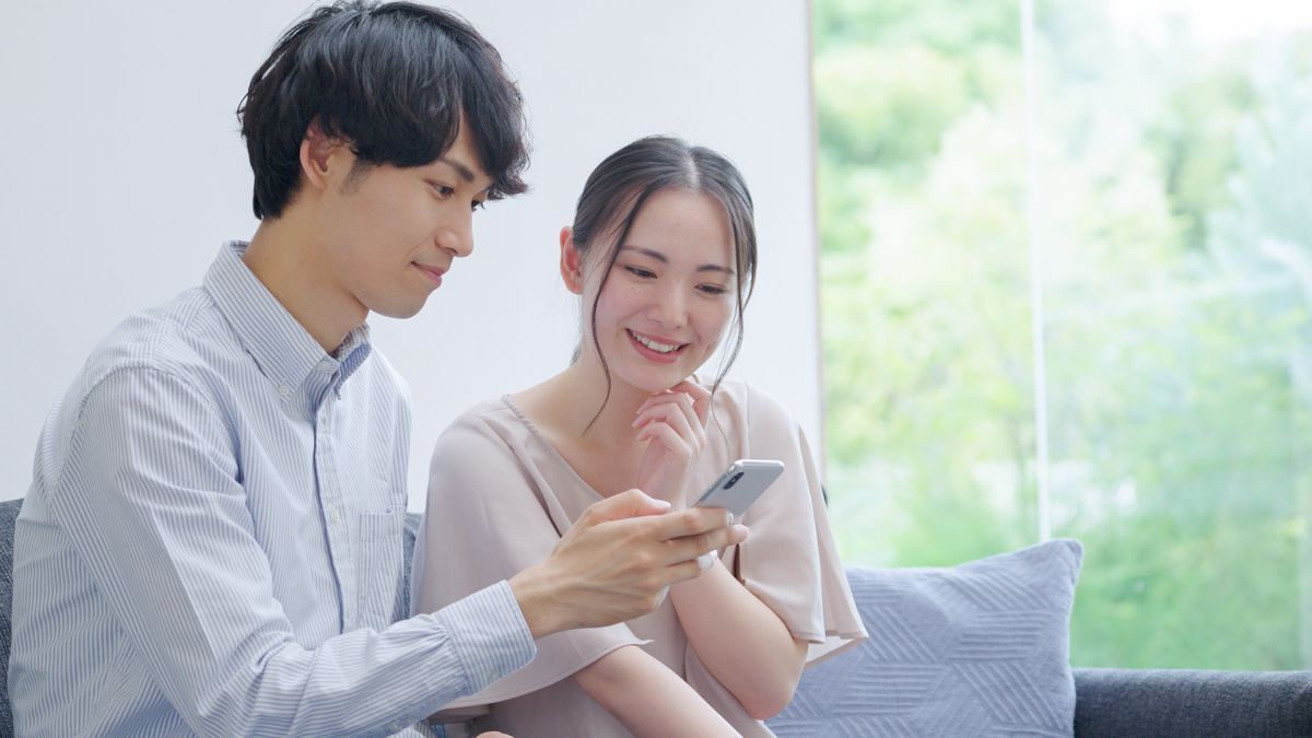 Asian man showing phone screen while sitting close to woman.