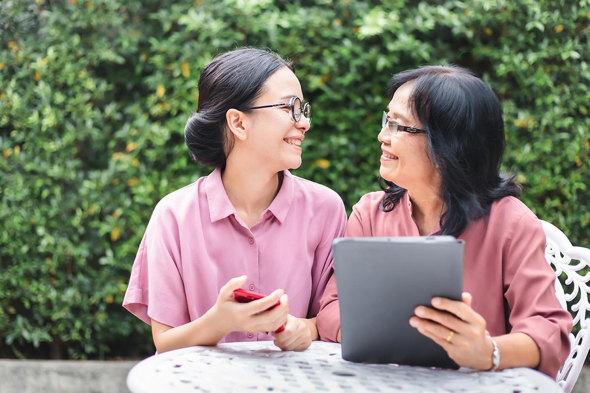 Asian mother and daughter smiling with tablet