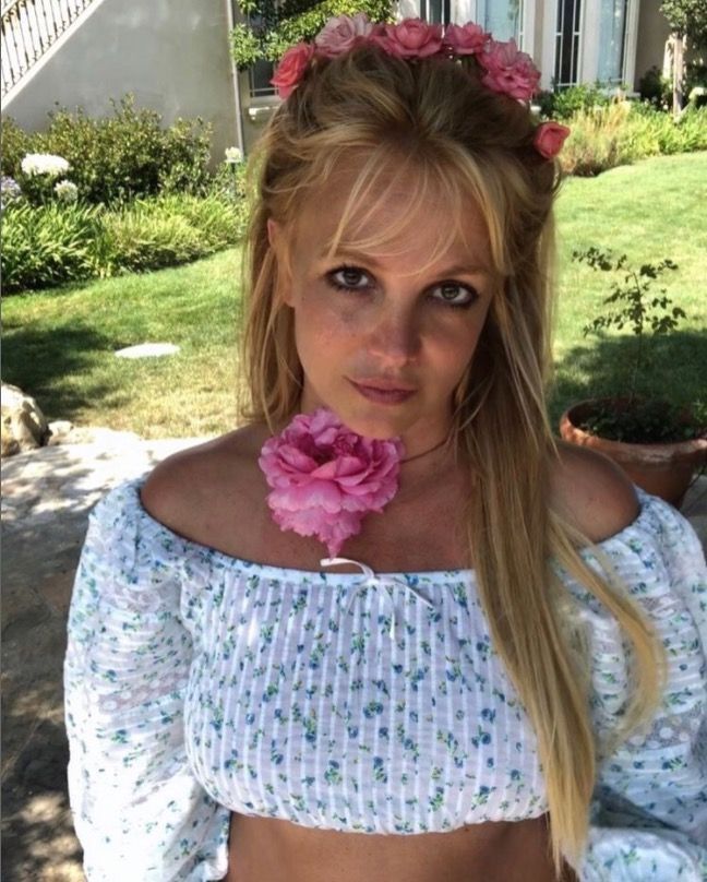 Britney Spears plays up feminine chic with curtain bangs, a half-up 'do, and flowers.