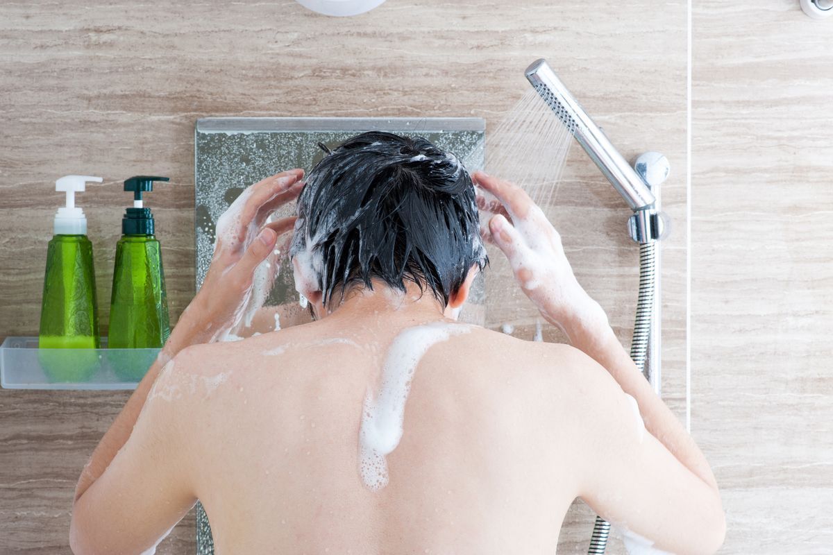 A man shampooing his hair in the shower.