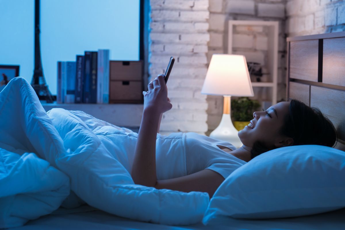 Asian woman using her mobile phone while in bed
