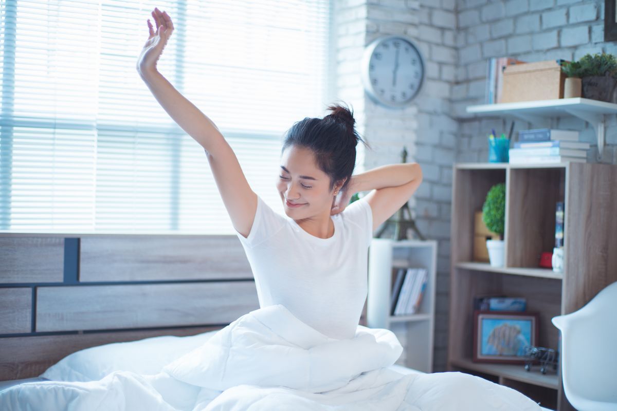 Asian woman waking up and stretching in bed
