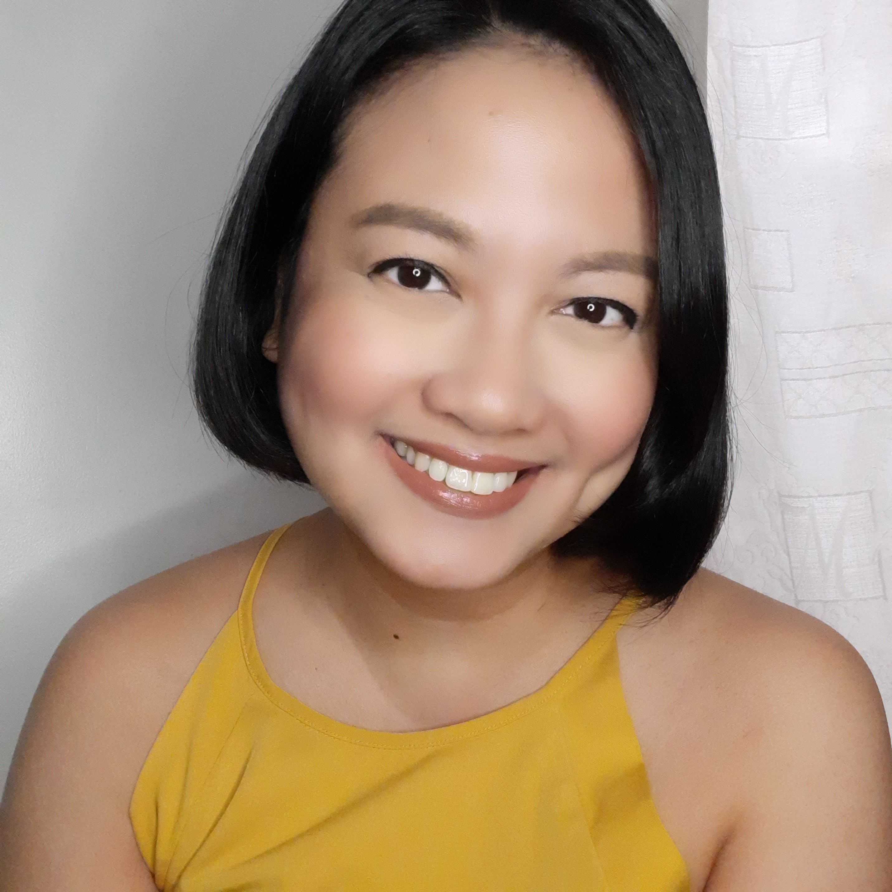 A beautiful woman in yellow top smiling at the camera.  