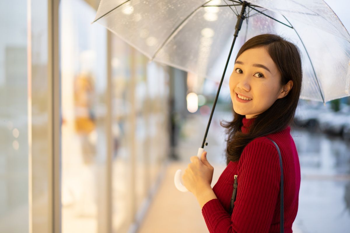 Woman in red sweater holding an umbrella.