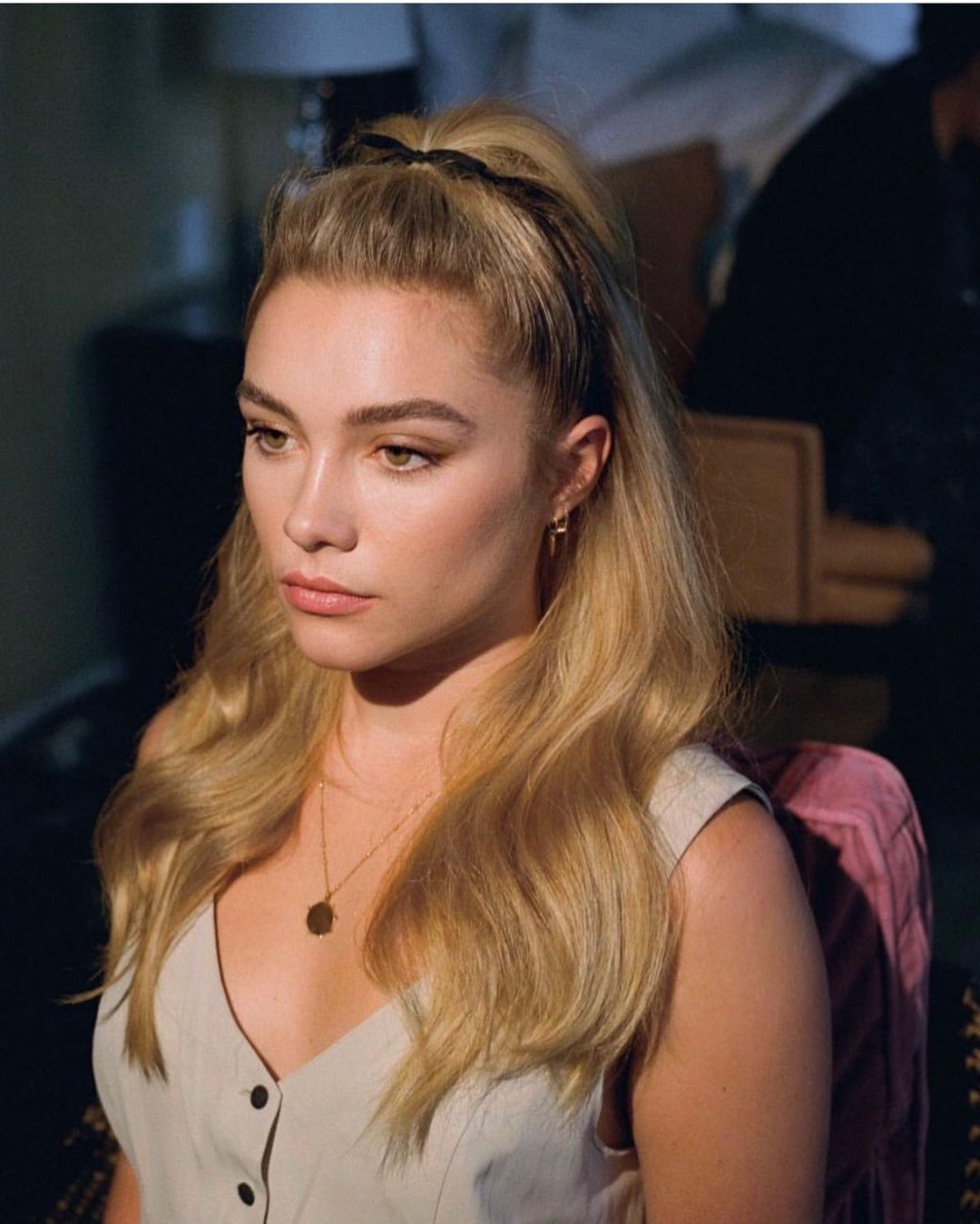 A portrait of Florence Pugh with half updo and pinned-back hair.