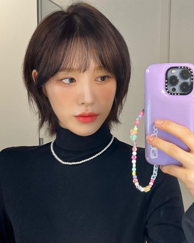 Wendy from Red Velvet with shaggy bob and black turtleneck taking a mirror selfie.
