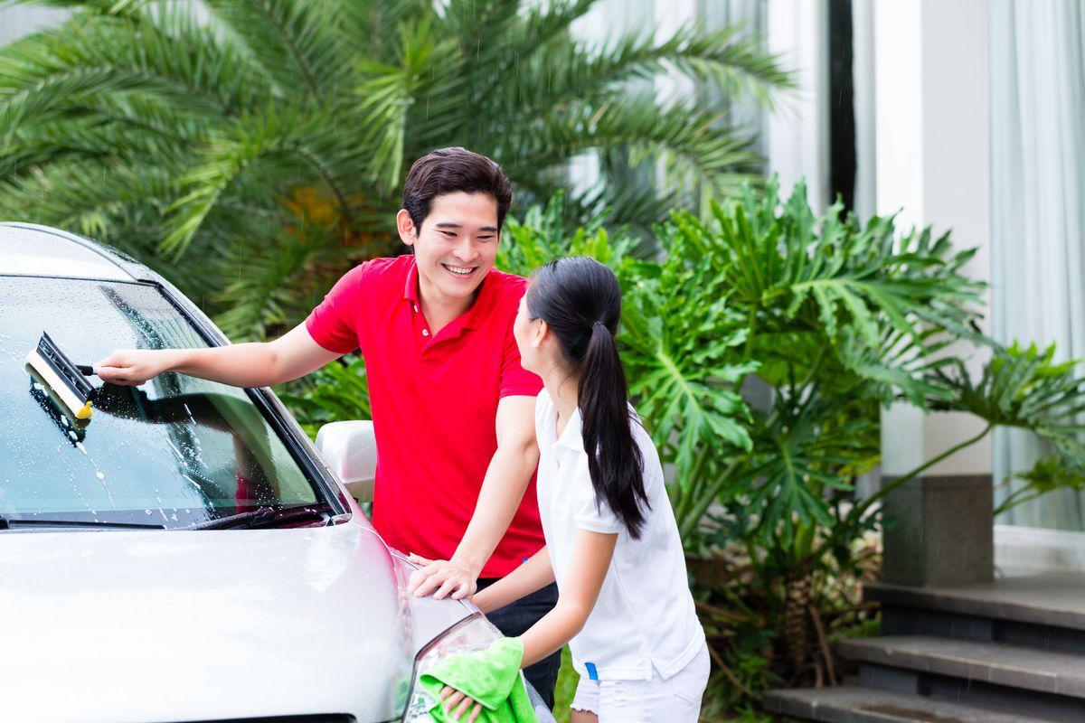 Asian man in red with woman in white washing car