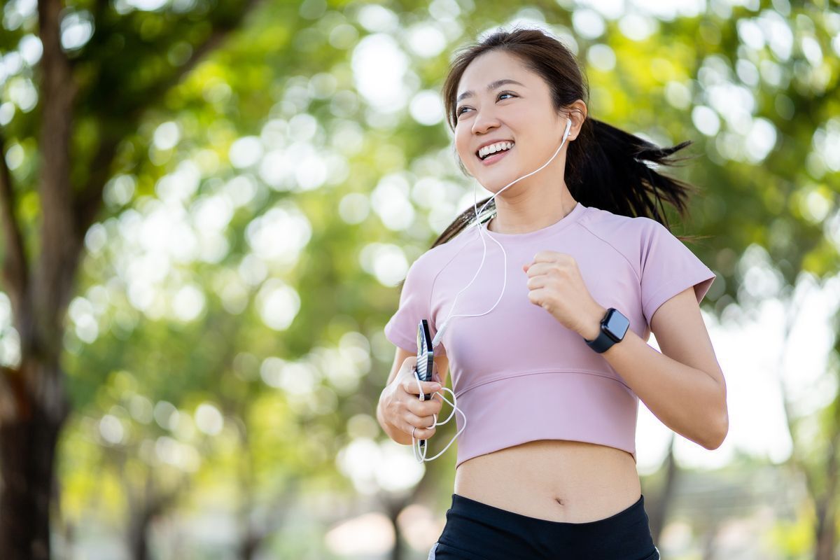 Fit Asian woman running, wearing a lilac cropped top.