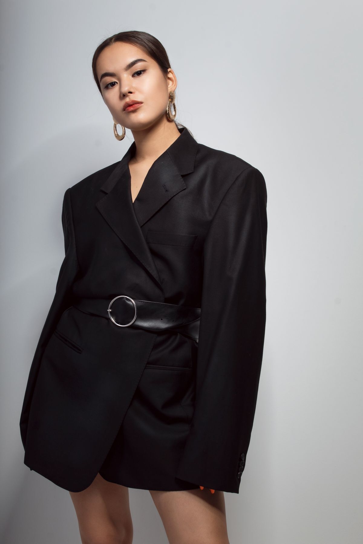 Asian woman wearing a black belted blazer.
