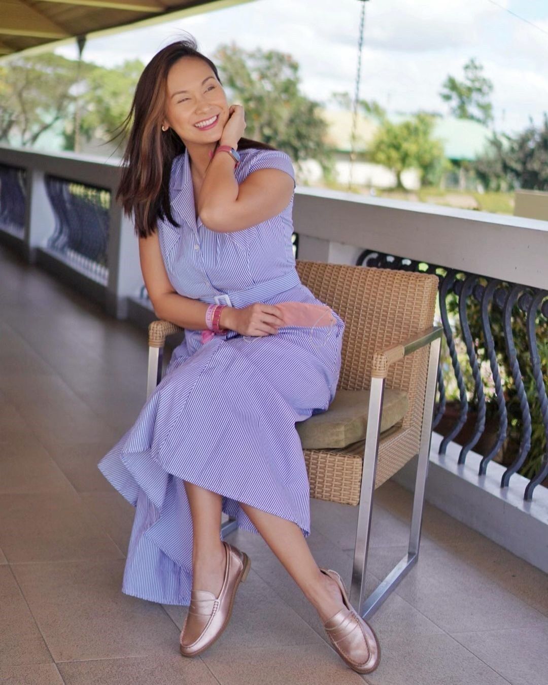 Asian woman in a purple dress sitting outdoors.