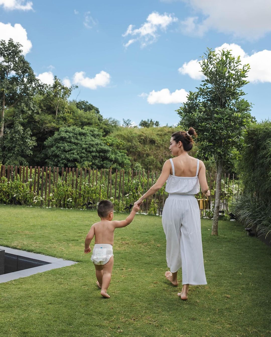 Asian mom with baby in diaper on the grass.
