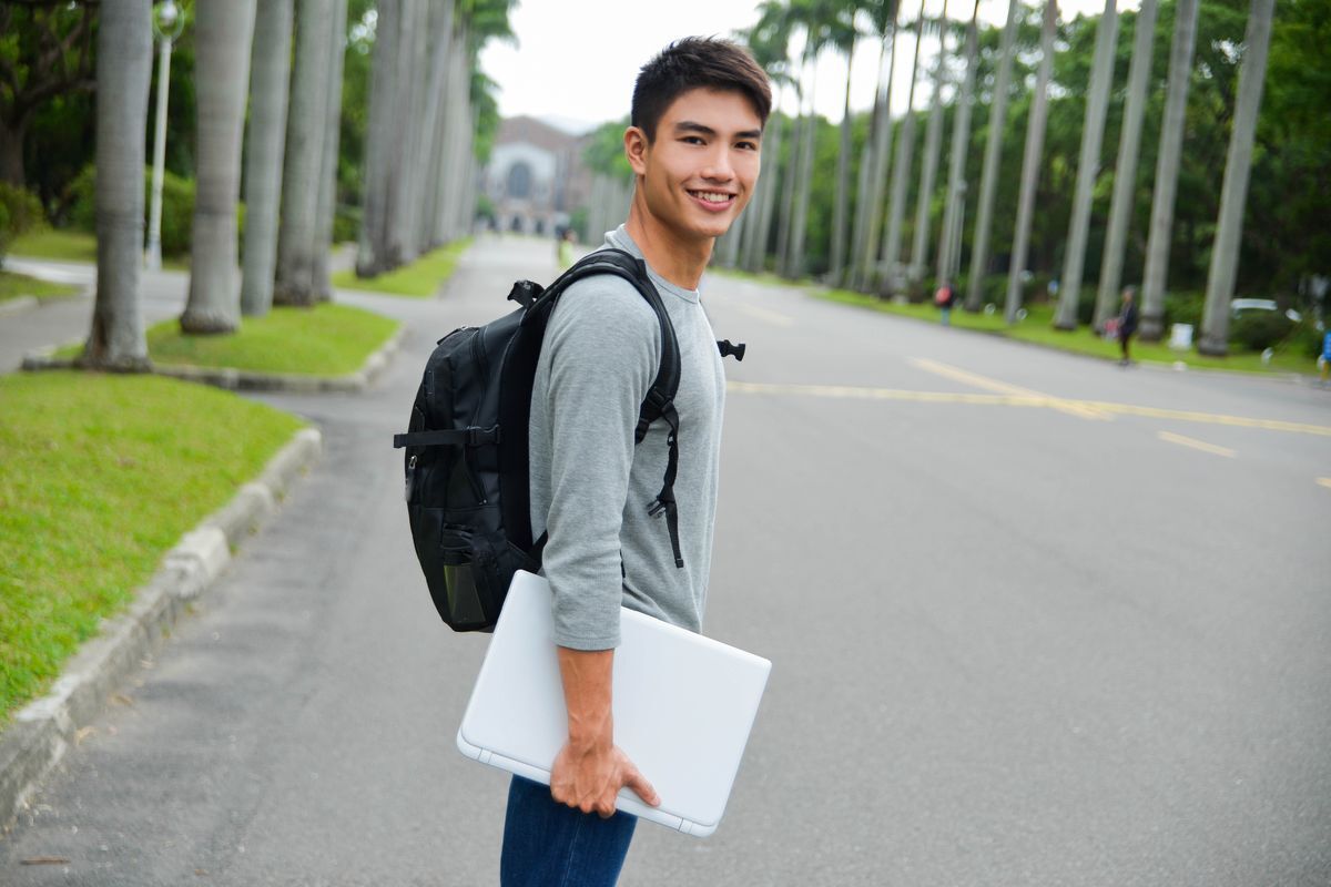 Asian man with backpack standing in middle of road
