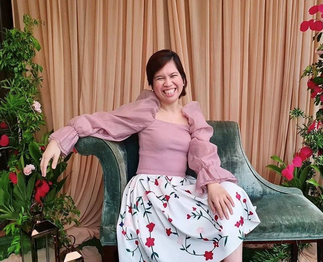 Smiling Asian woman in a floral skirt and pink top sitting