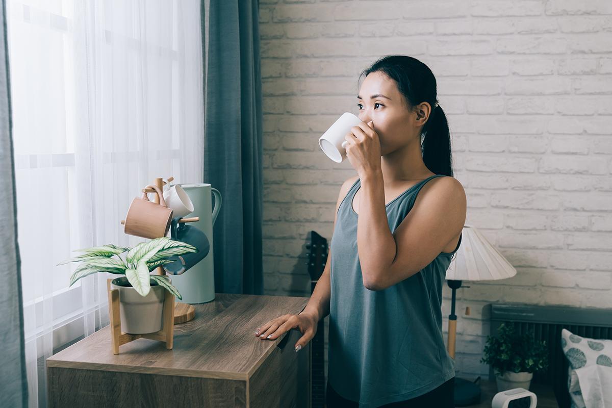 Asian woman sipping coffee at home