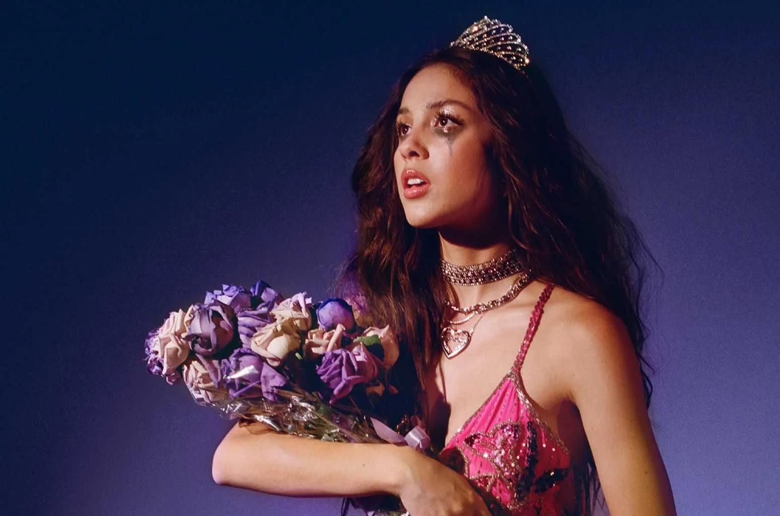 Teenage girl with a tiara holding a bouquet of flowers, with mascara on her face.