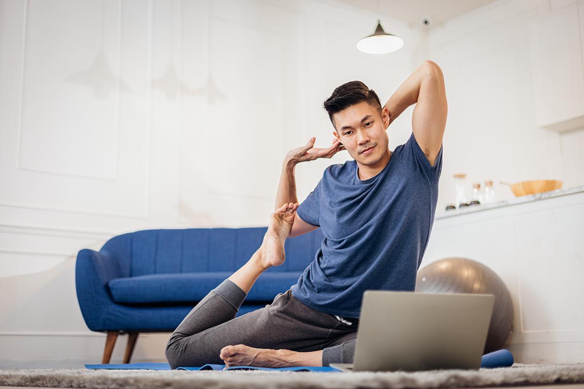 Asian man practices yoga inside his home