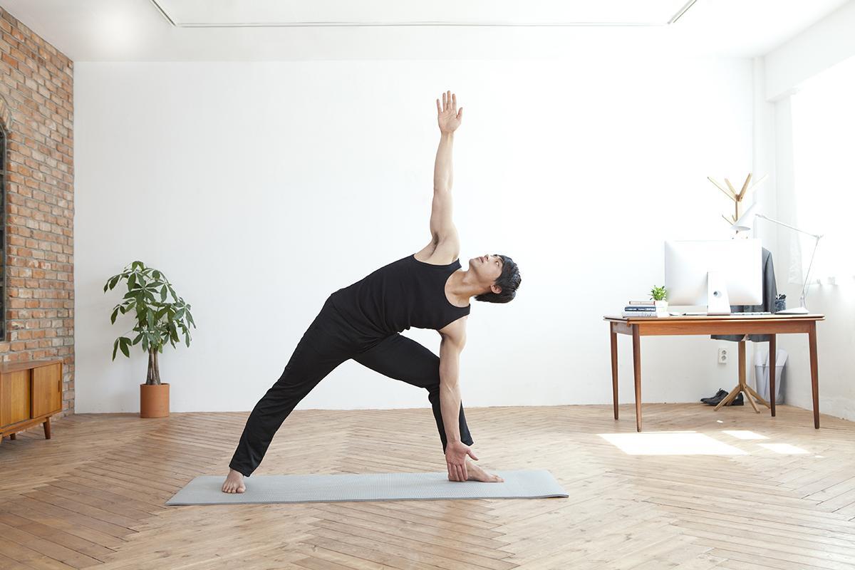 Asian man does yoga inside his living room