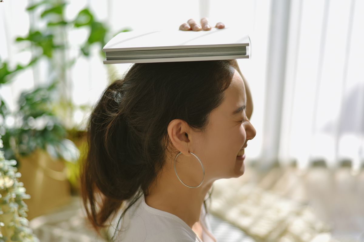 Asian woman balancing a book on her head