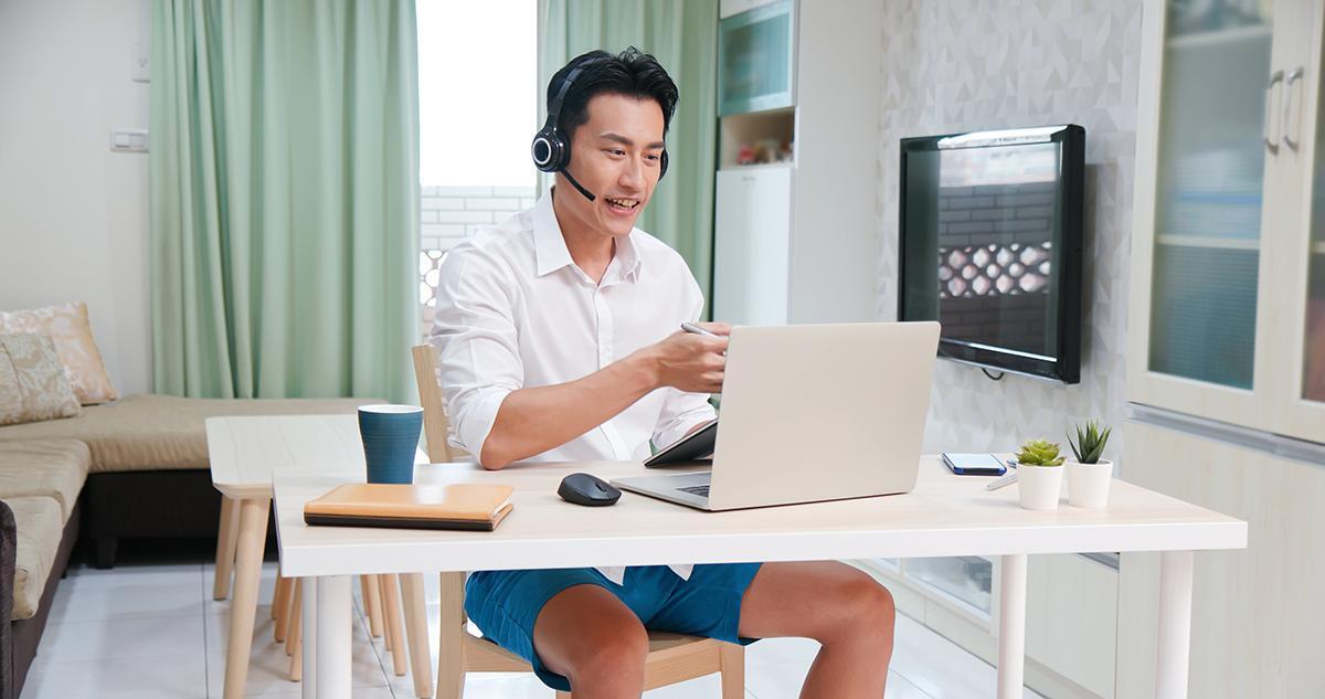 Asian man with headphones in front of a laptop