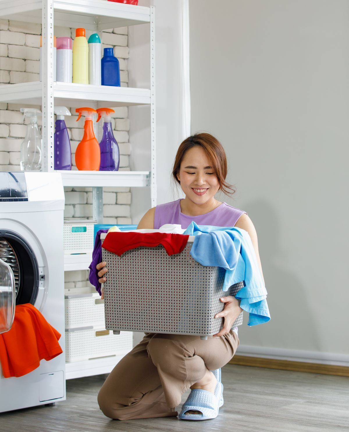 Asian woman holding a laundry basket happily doing laundry. 