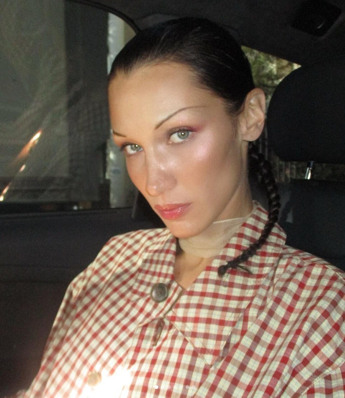 A woman with braided hair, wearing a checked shirt. 