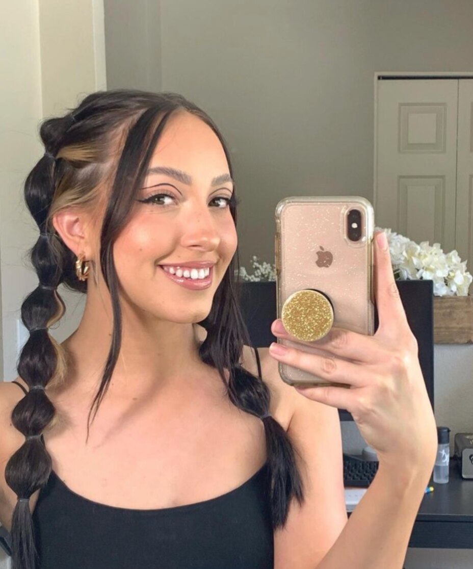A woman with bubble braids doing a mirror selfie. 