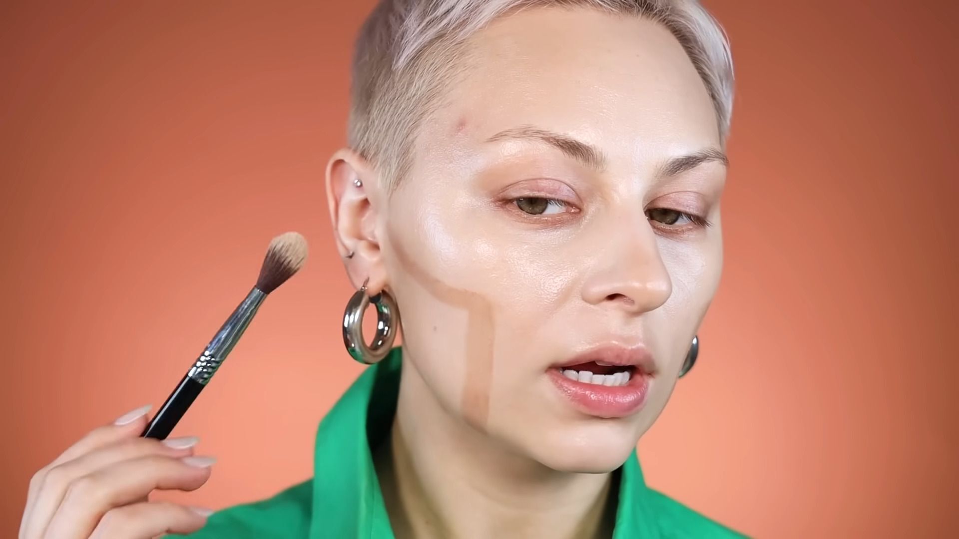 Woman with brown contour lines on her cheek holding a makeup brush. 