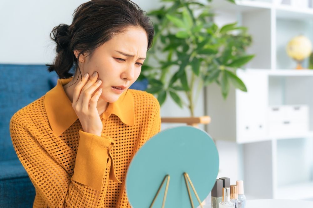 Woman touching her face in front of the mirror.