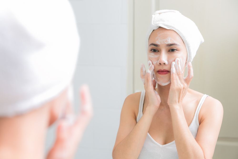 Woman washing her face with facial foam in the bathroom.