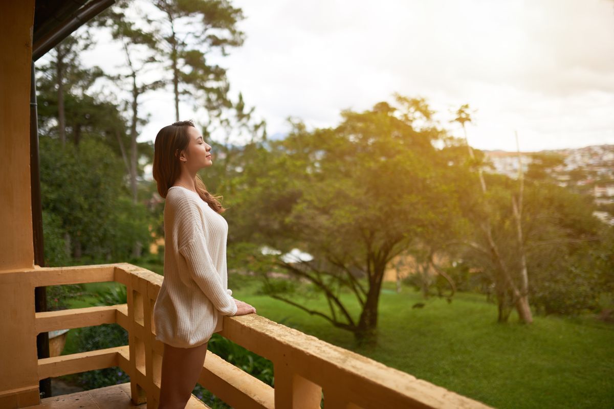 Asian girl on the terrace looking out and breathing deeply.