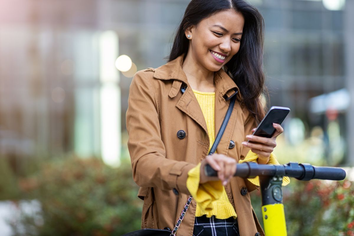 Filipino woman with a scooter looking at her phone