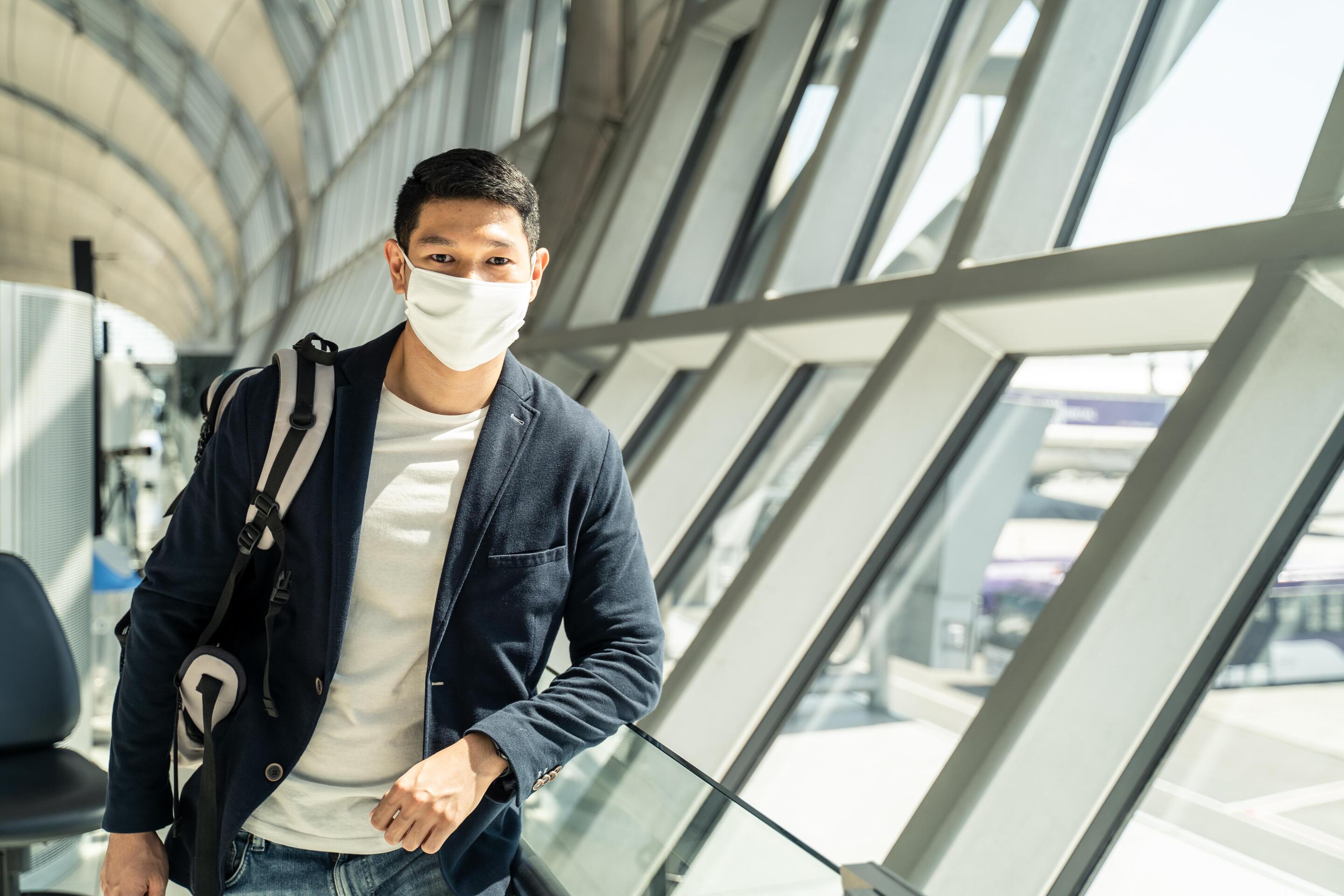 A young Asian man wears a mask while traveling.