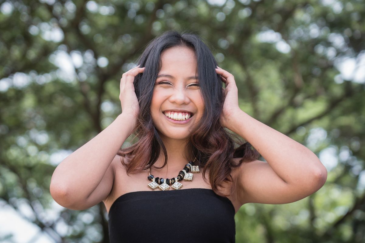 A woman with Filipino physical traits stands outside on a sunny day.