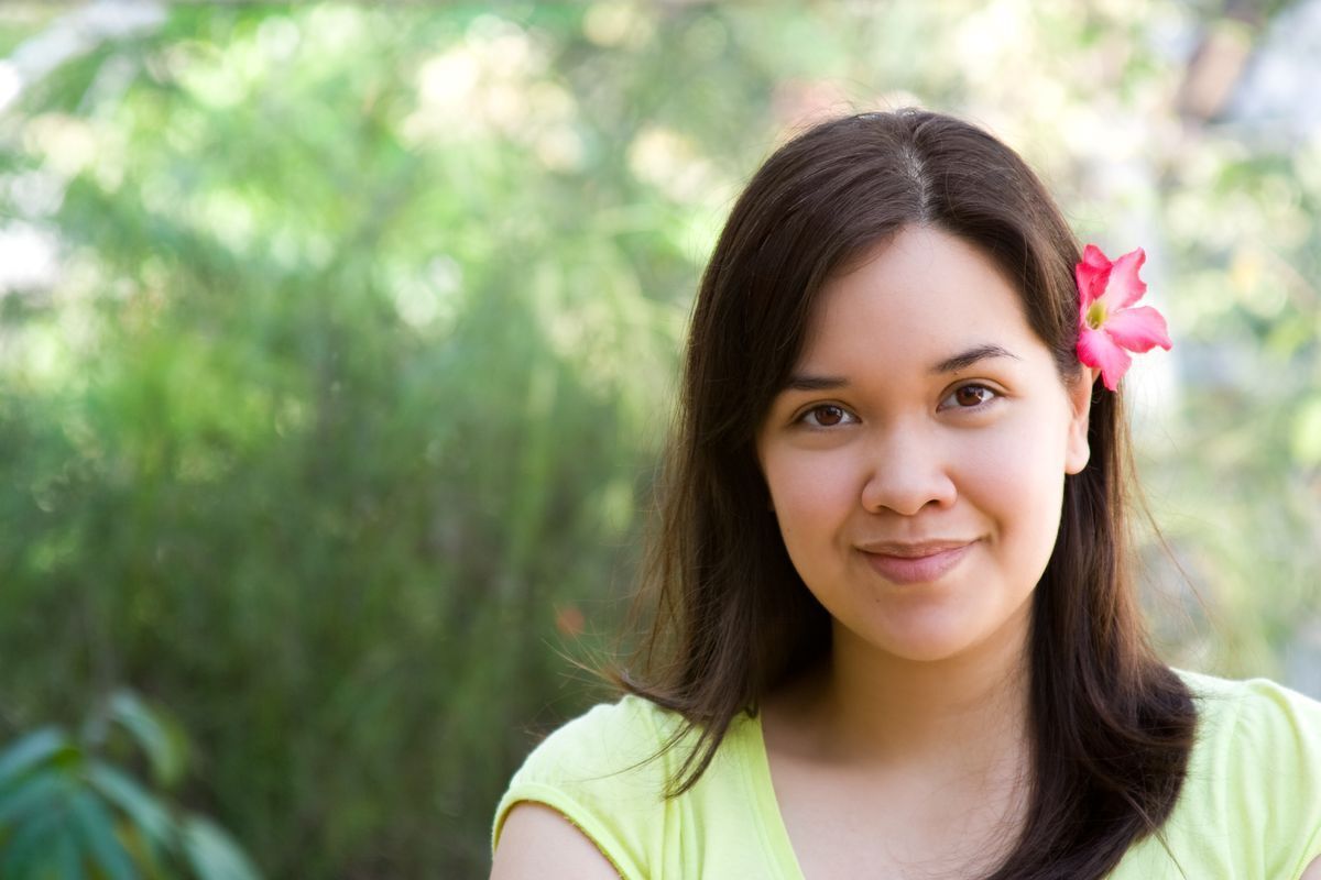 Smiling Asian woman with a flower tucked behind her ear.