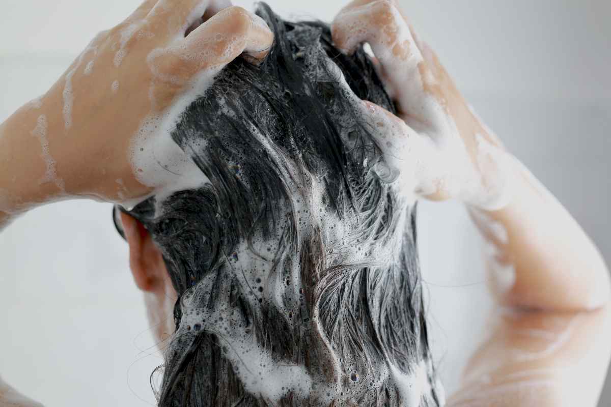 The back of an Asian woman shampooing her hair.