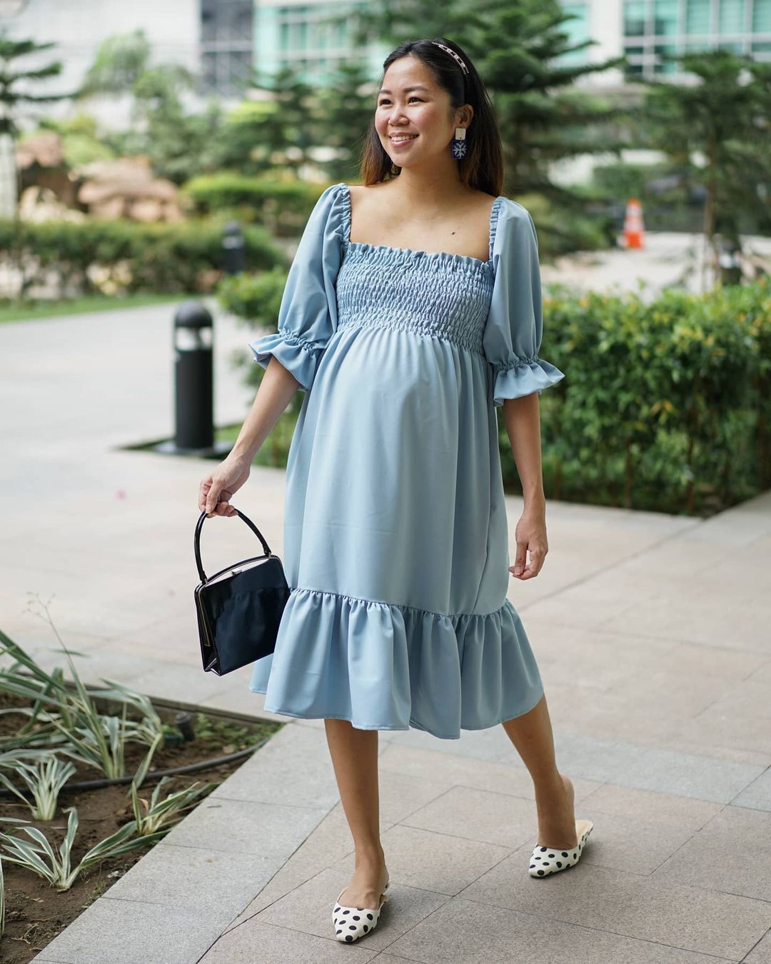 A pregnant woman wearing a blue dress walking on a pedestrian walkway