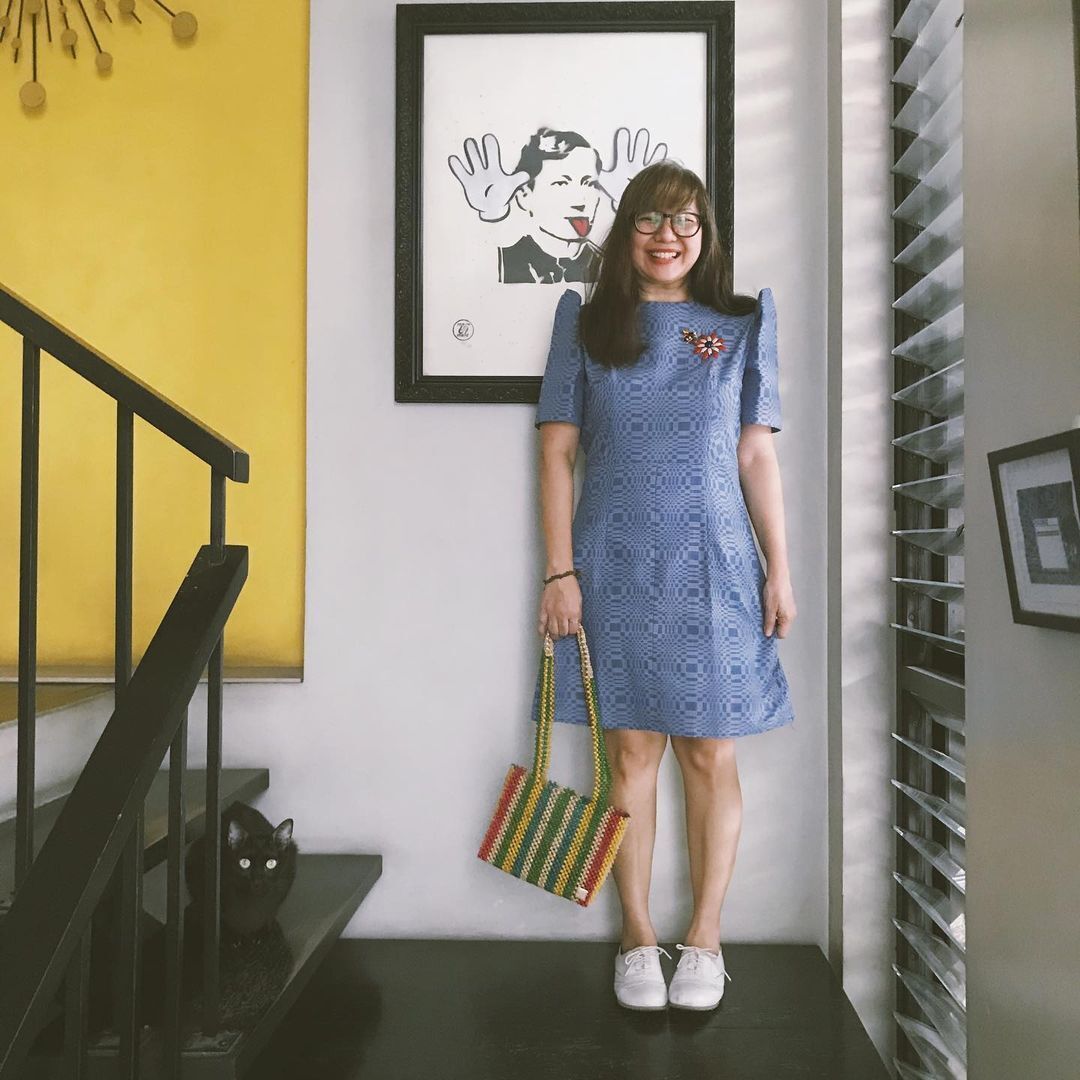 A woman in a blue dress and white shoes posing with a cat