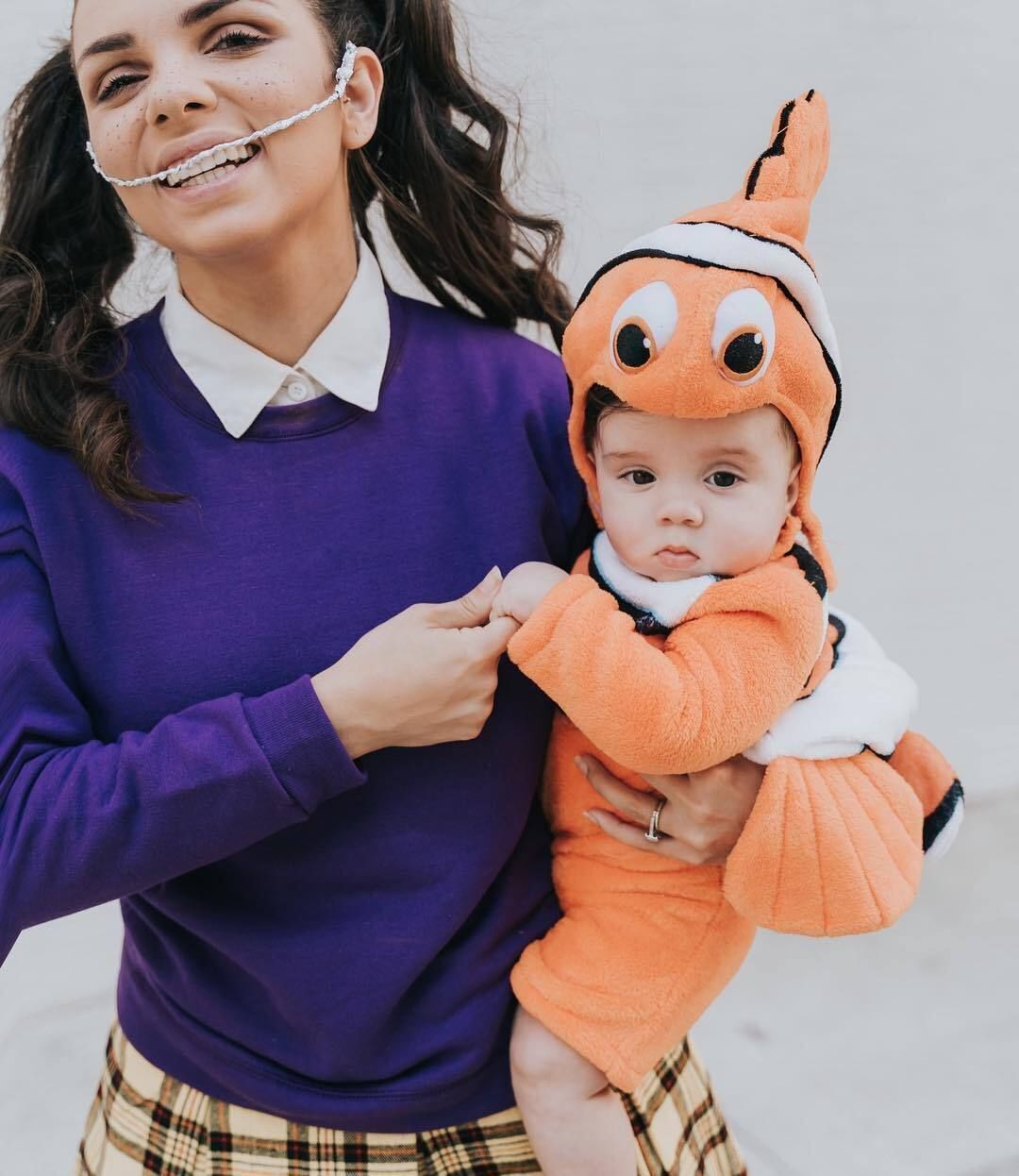 Woman in purple sweater holding her baby dressed as Nemo from Finding Nemo.
