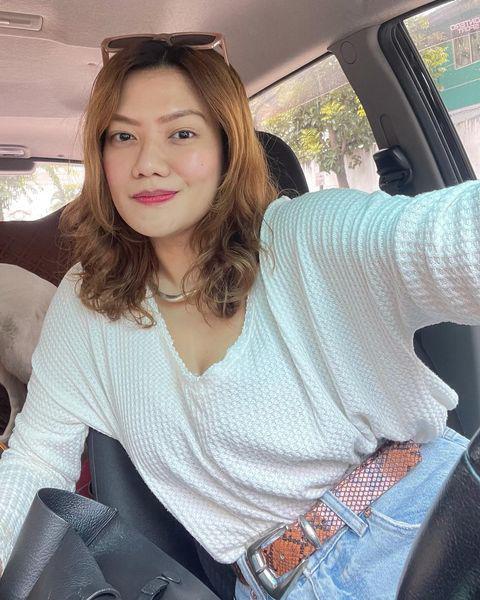 Blonde haired Asian woman taking selfie in a car